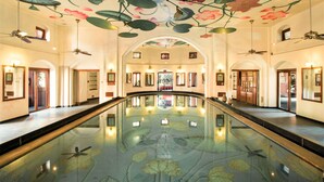 A spacious lobby with a central reflective pool, arched doorways, and ceiling artwork depicting flowers and insects.