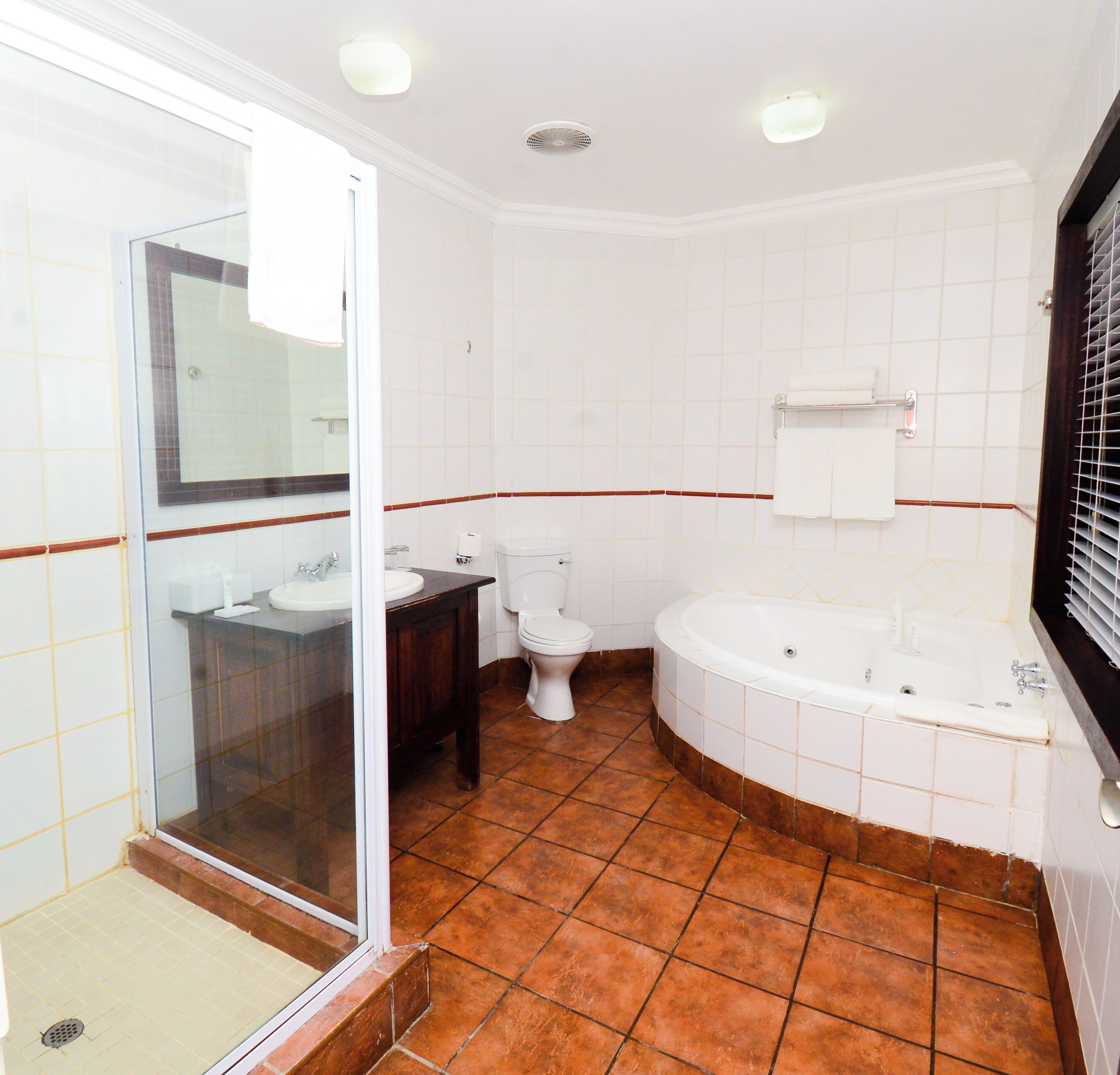 A bathroom with a glass shower enclosure, a sink, a toilet, and a bathtub.
