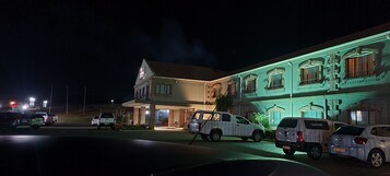Un hotel con una entrada destacada, varios espacios de estacionamiento y una fachada bien iluminada.