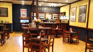 Een gezellig restaurantinterieur met houten tafels en stoelen, een bar en een menubord aan de muur.