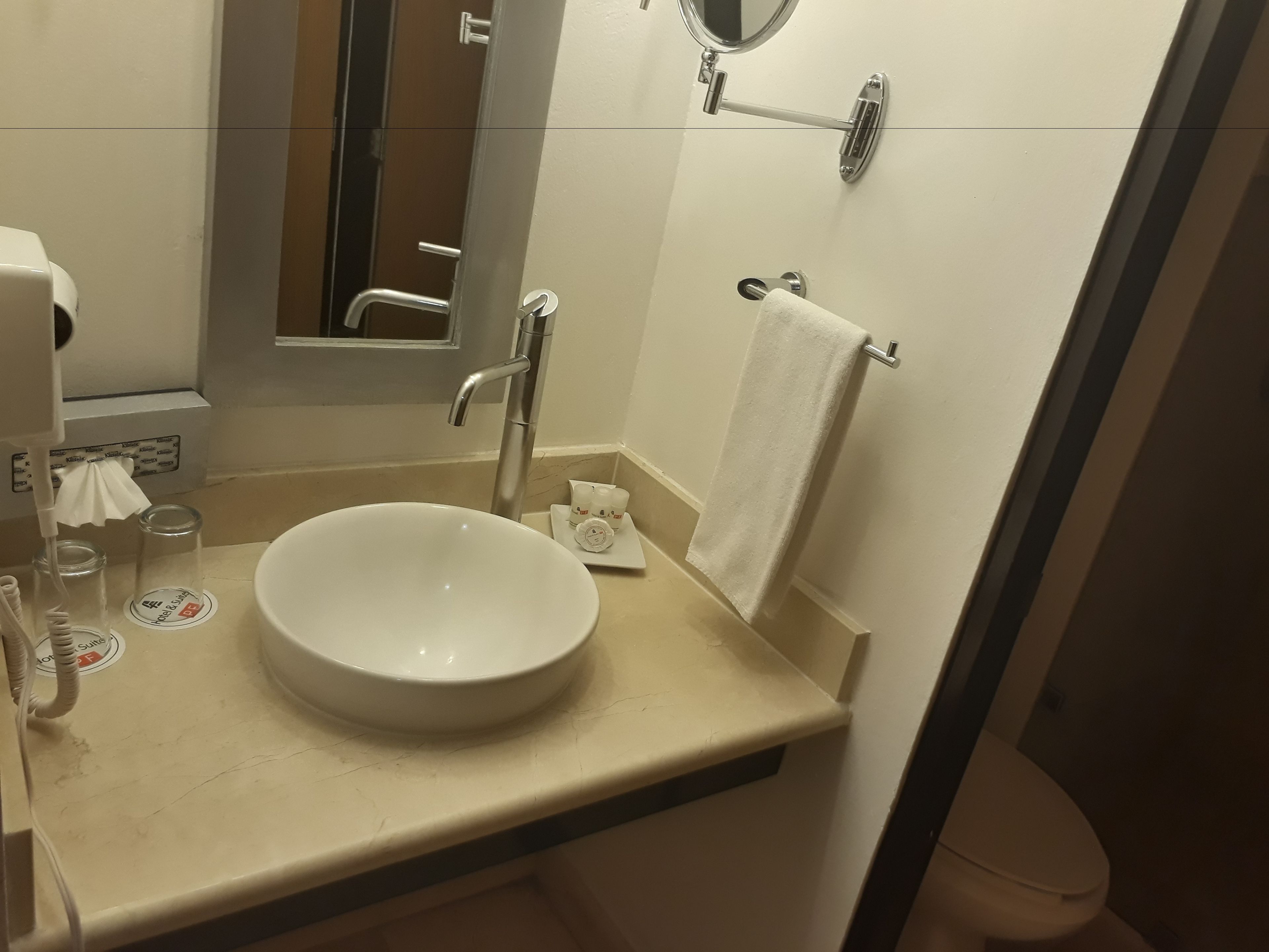 A bathroom with a white sink, a mirror, a towel rack, and a toilet.