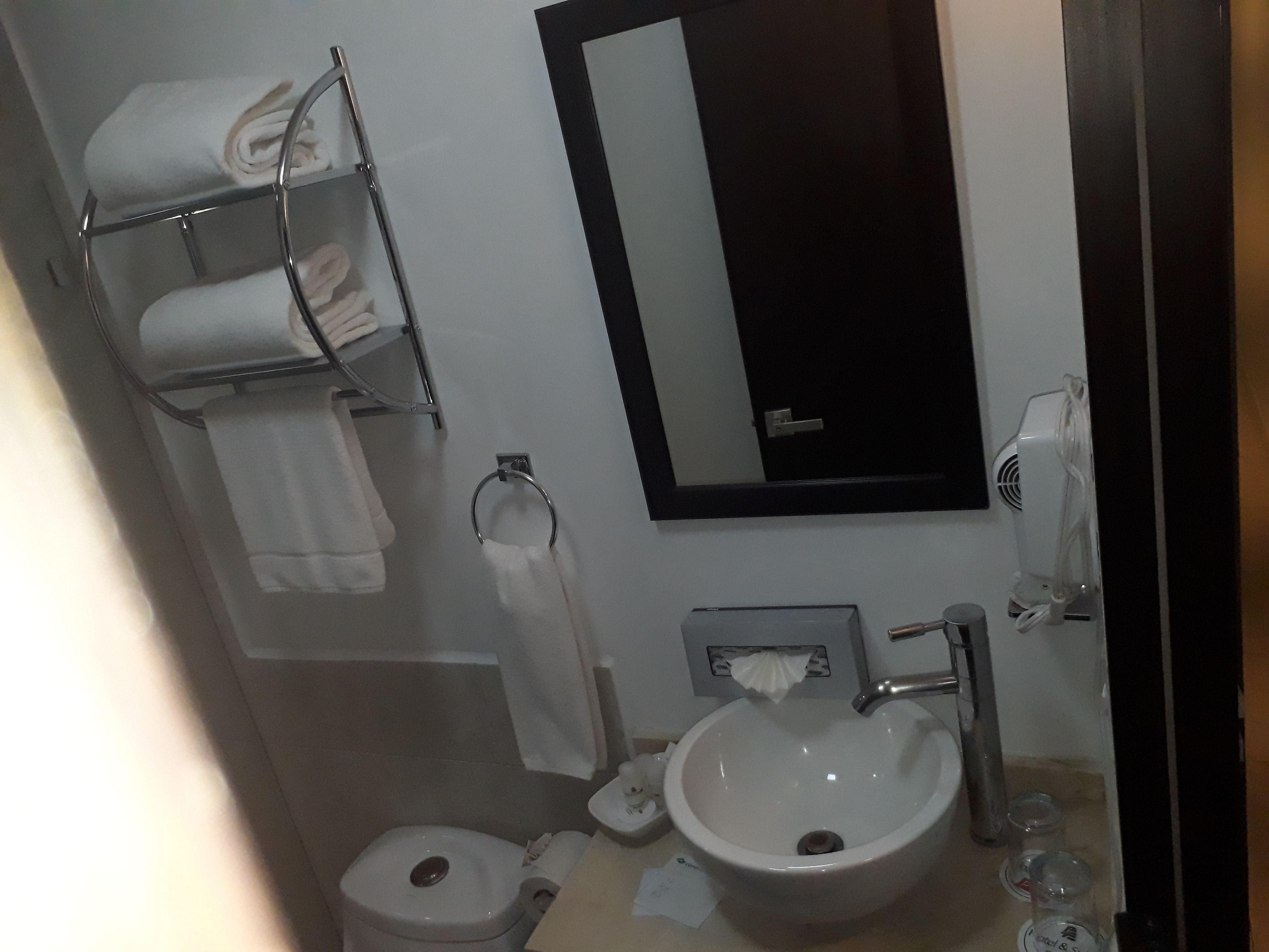Casa de banho com lavatório, sanita, porta-toalhas e espelho.