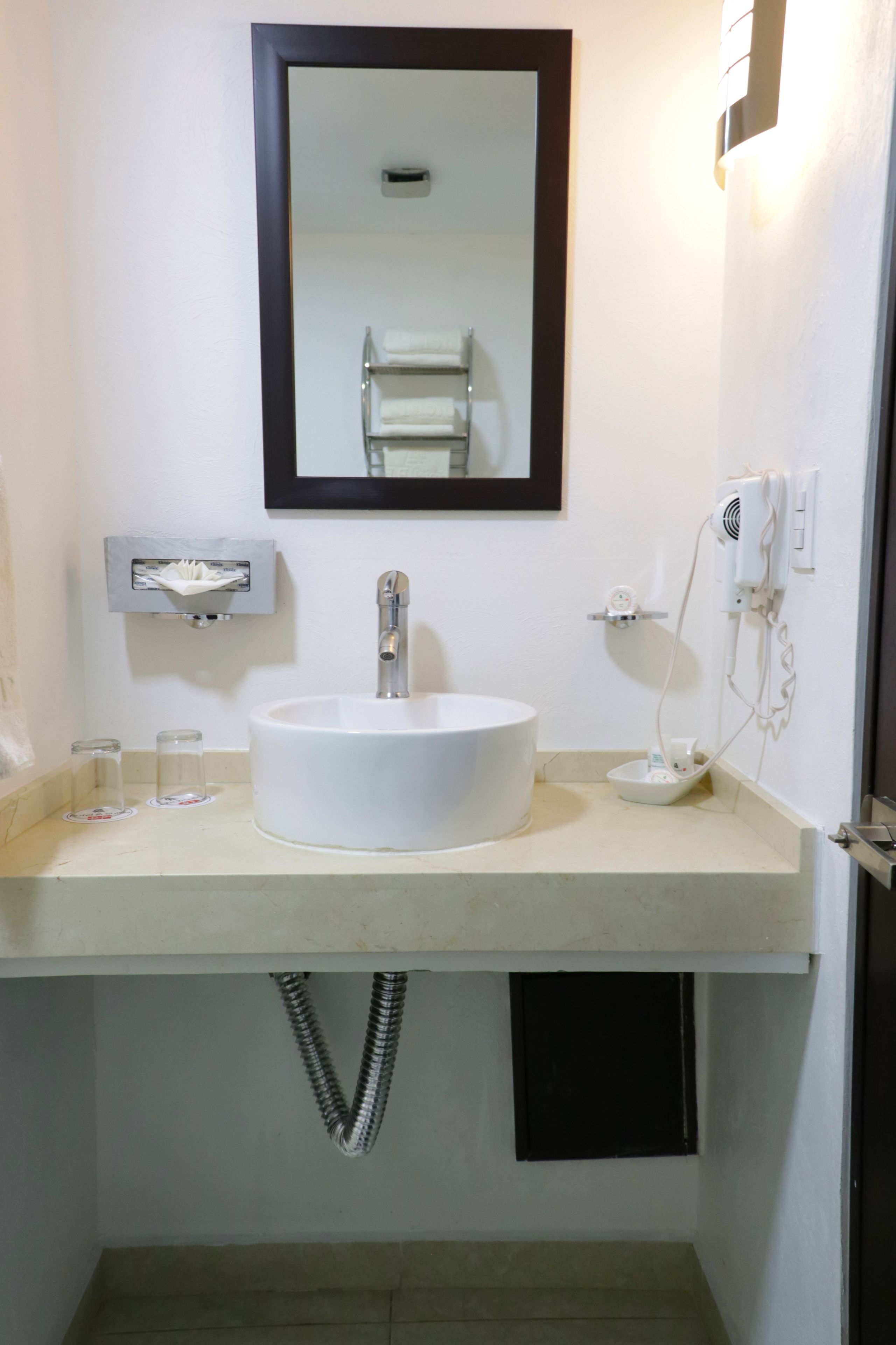 Une salle de bain avec un lavabo blanc, un miroir et un porte-serviettes.