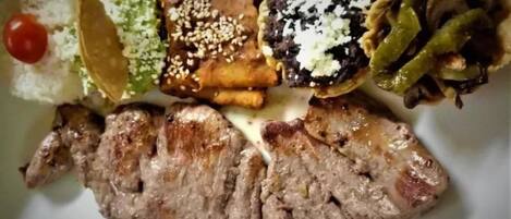 A plate with grilled steak, rice, and various vegetables.