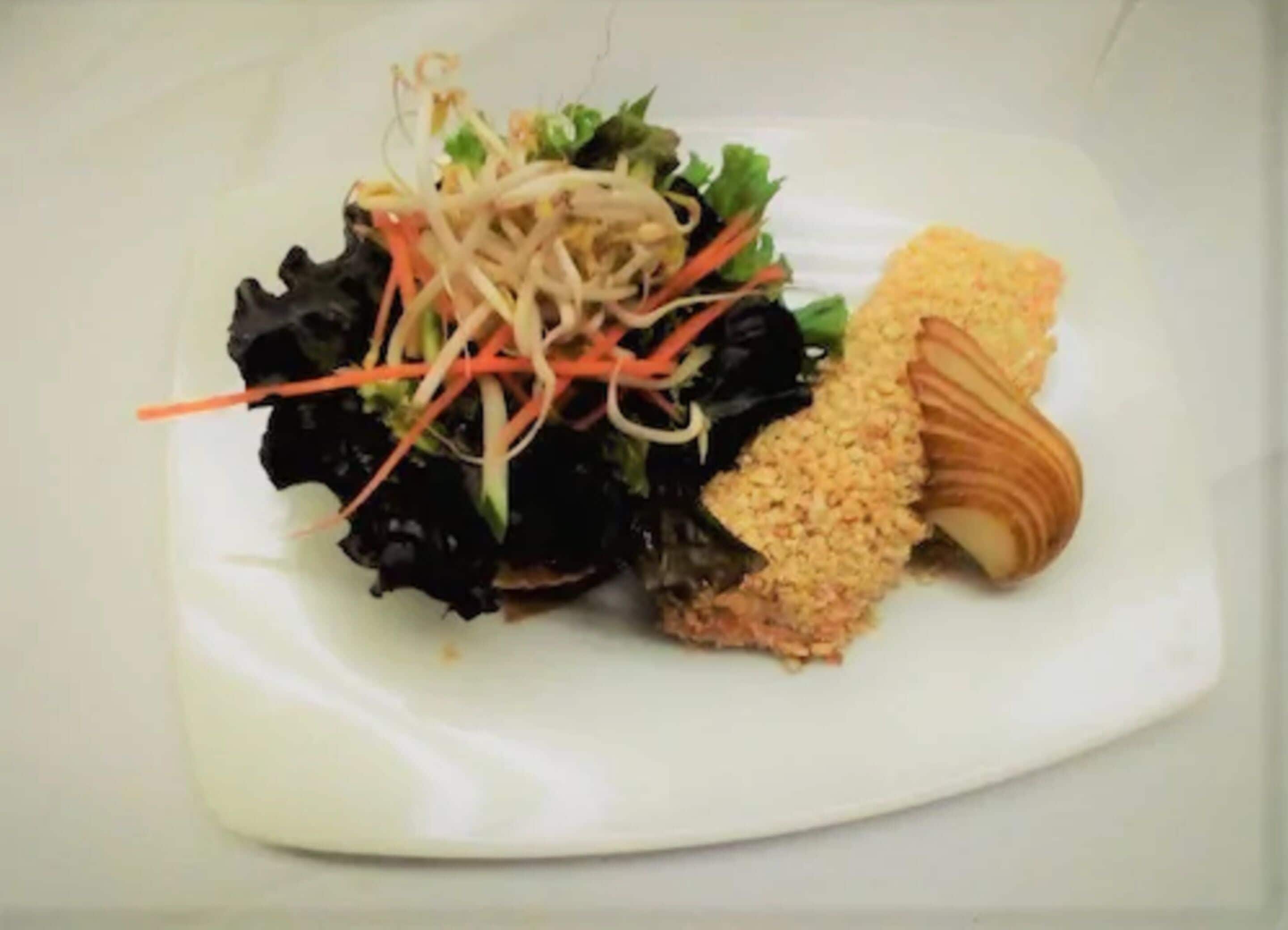 A plate with a salad, a breaded item, and a piece of meat.