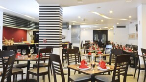 A restaurant with multiple dining tables, chairs, and a kitchen area.