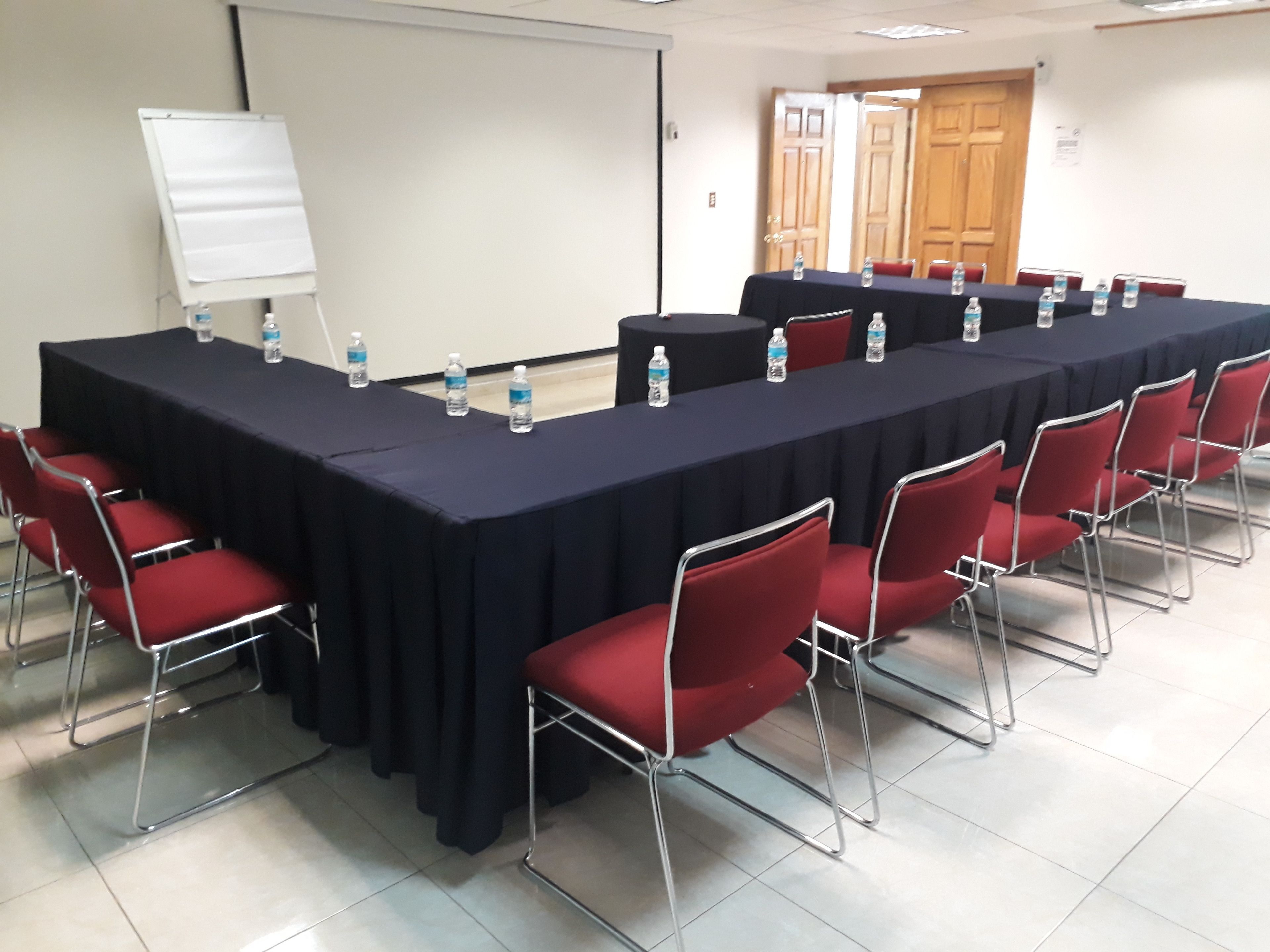 A conference room with a long table, red chairs, and water bottles.