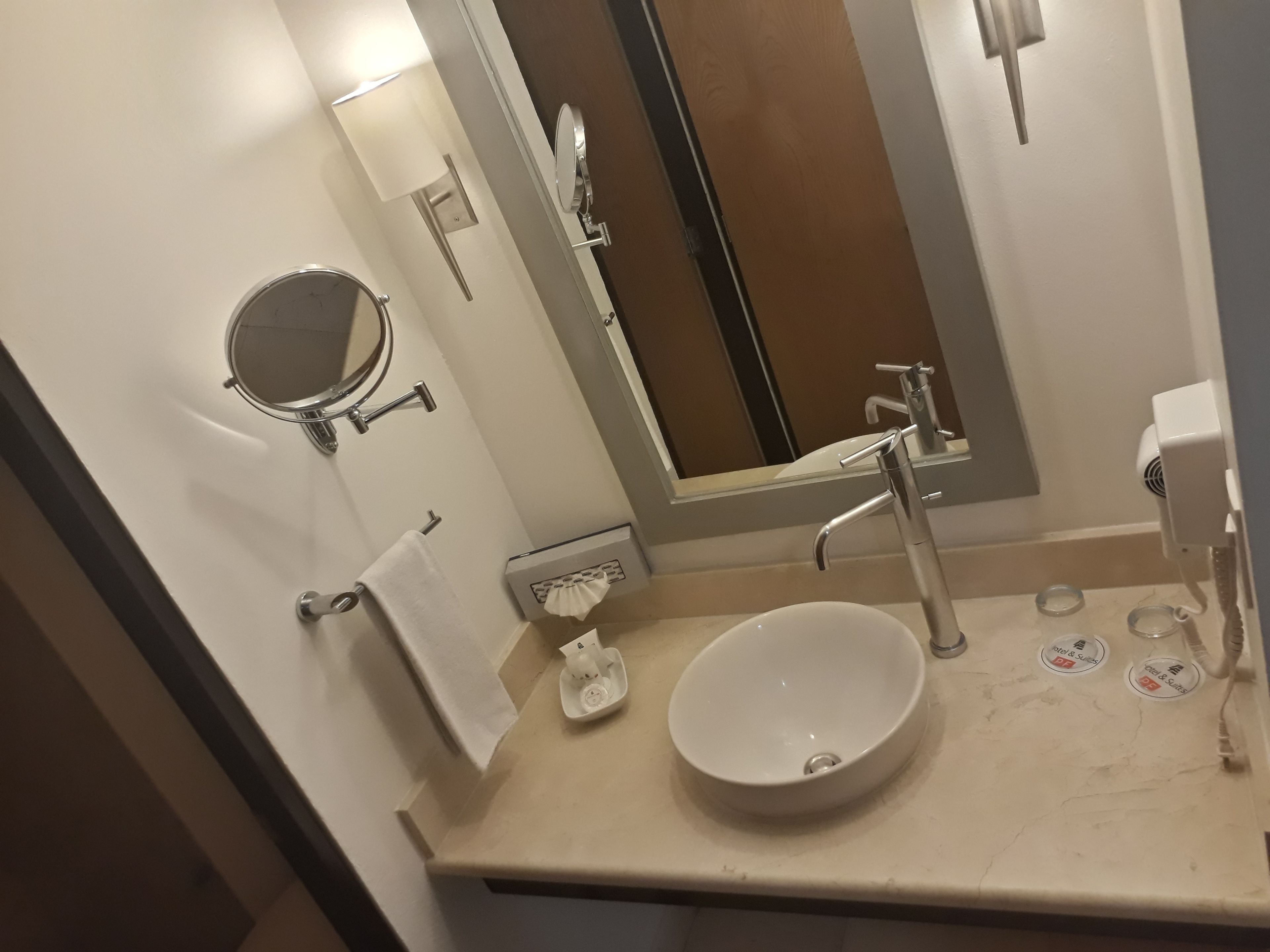A bathroom with a sink, mirror, towel rack, and a hand dryer.