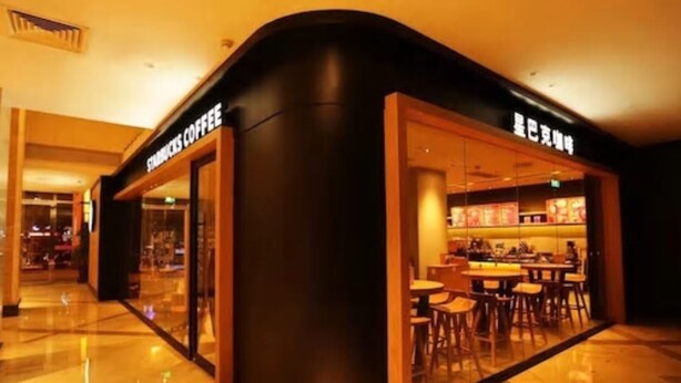 Een Starbucks Coffee winkel met een modern ontwerp, met een gebogen gevel en grote glasramen.