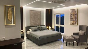 Een moderne slaapkamer met een groot bed, nachtkastjes, een stoel en kunstwerken aan de muur.