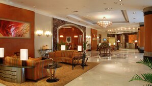Een hotel lobby met een bank, een glazen tafel en een receptiebalie.
