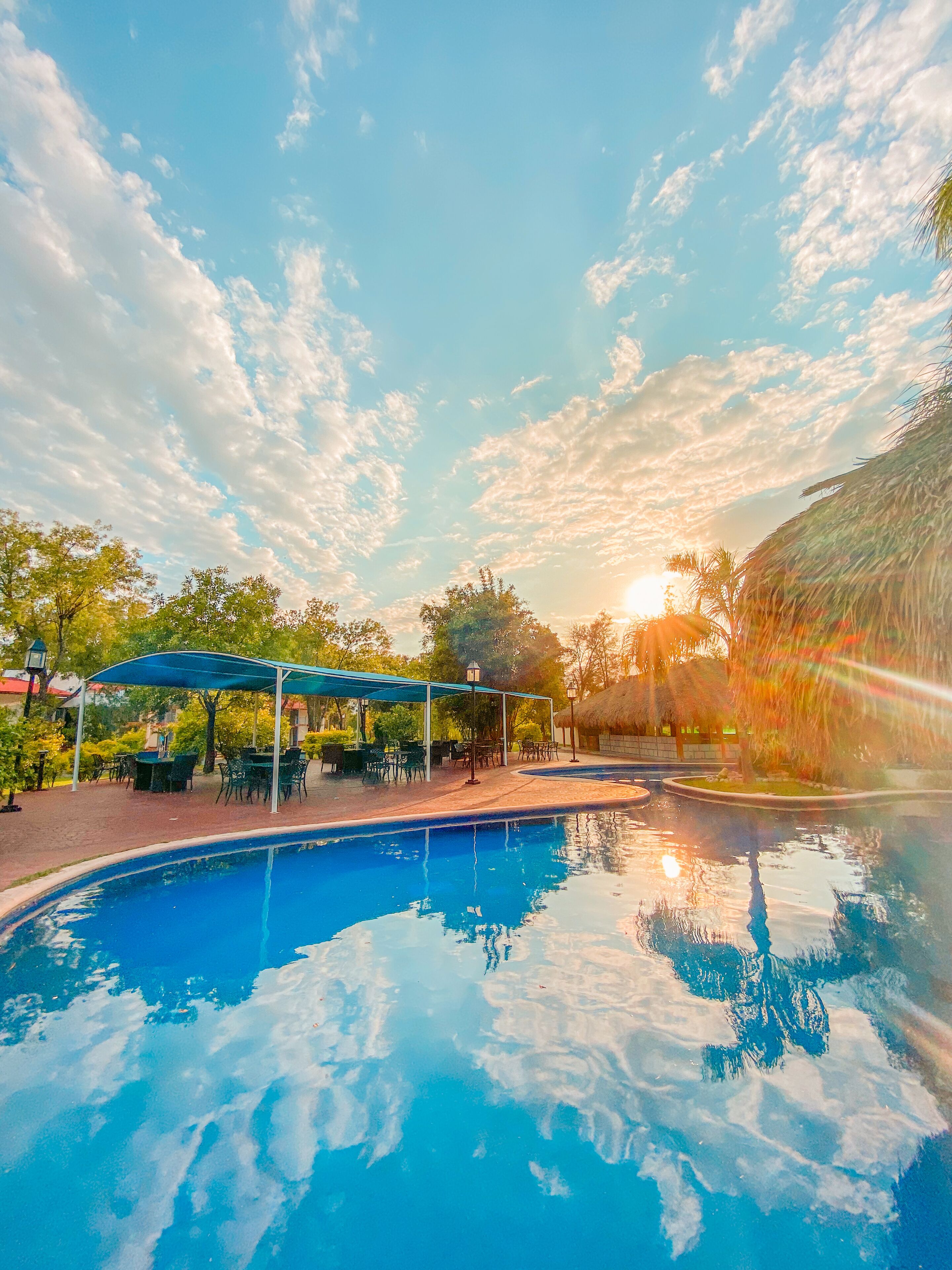 A swimming pool with a blue sky and clouds in the background.