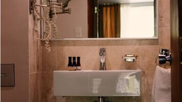 Un baño con un lavamanos blanco, un espejo y un perchero para toallas.
