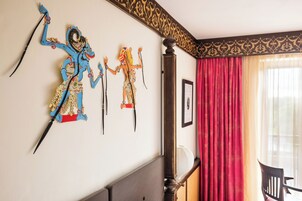 Una habitación con una cama, una silla y una pared decorada con estatuas coloridas.