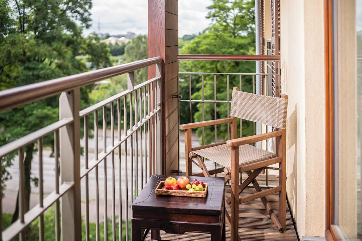 Une chaise et une table en bois sur un balcon, avec un panier en osier contenant des fruits.