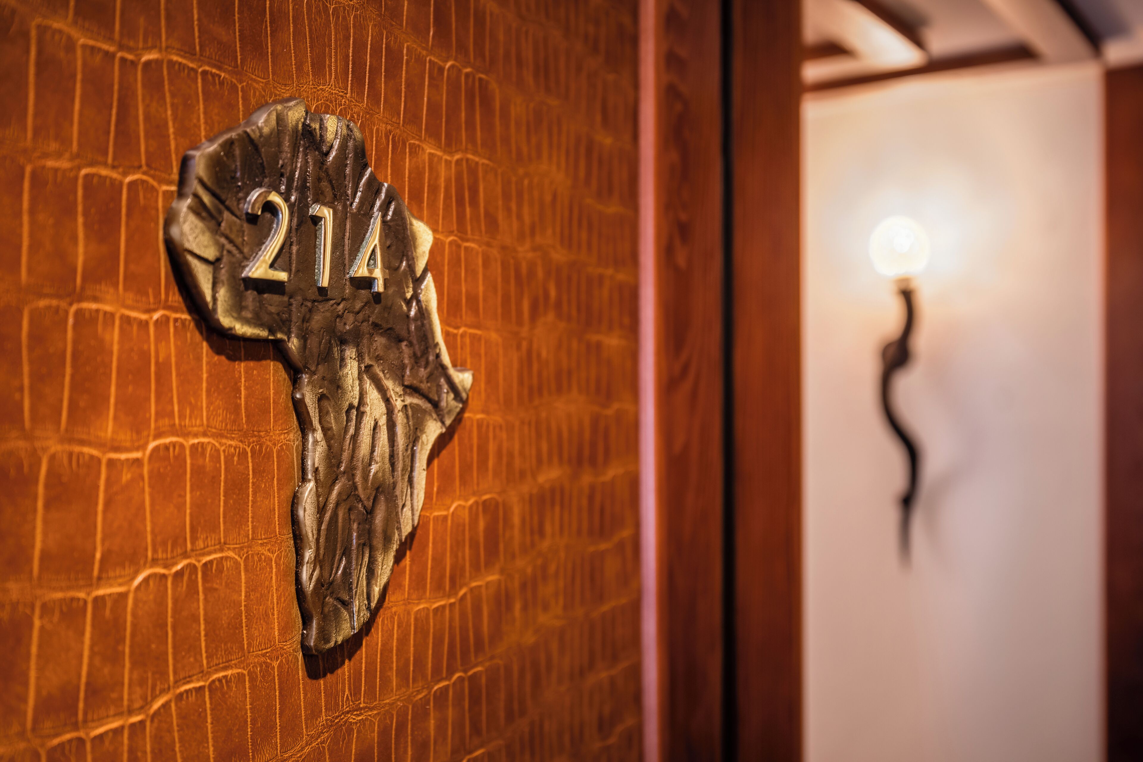 Une porte avec une plaque portant le numéro « 214 » et un luminaire au design incurvé.