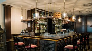 Un área de bar con varios taburetes, una barra y lámparas colgantes.