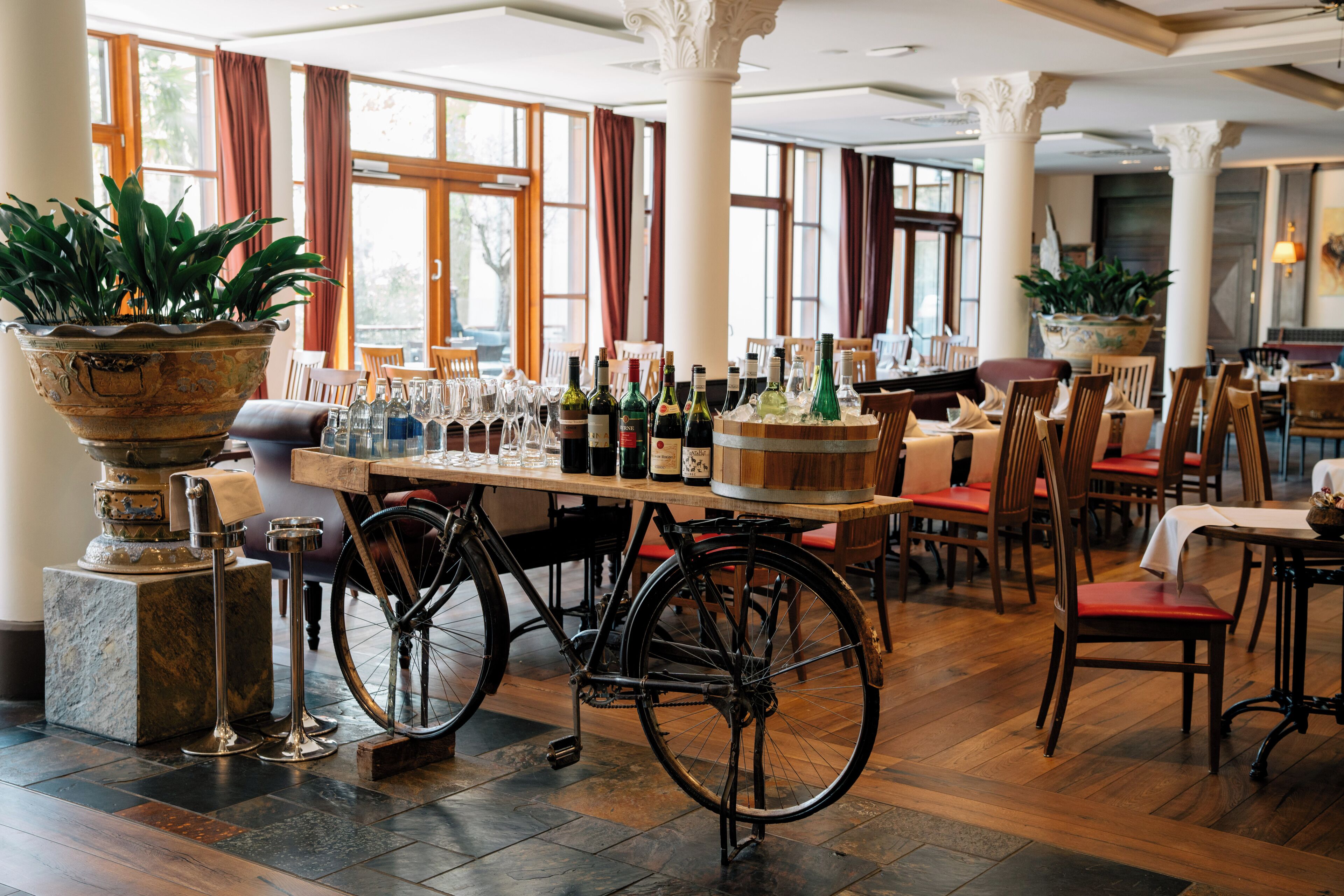 A restaurant interior with wooden tables, chairs, and a bicycle wheel as a decorative element.