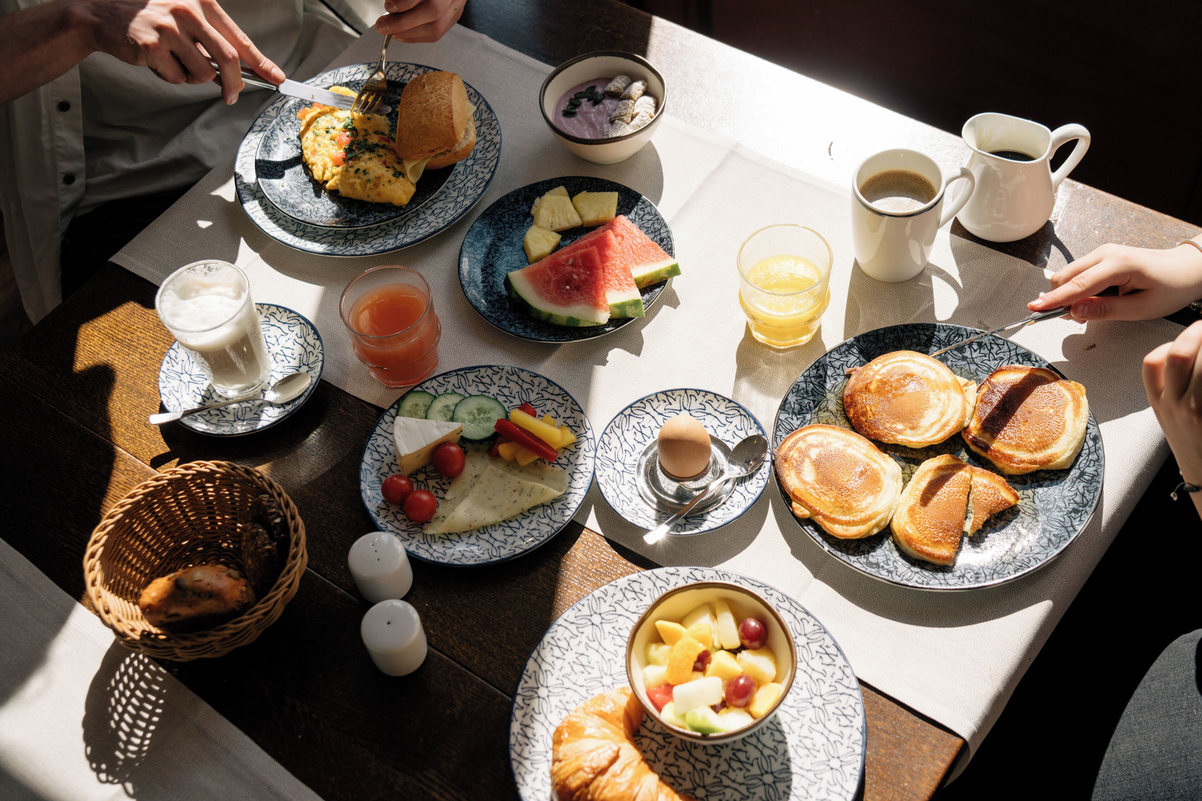 En frukostuppdukning med tallrikar fyllda med mat, en kaffekopp och ett glas juice.