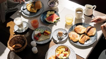 En frukostuppdukning med tallrikar fyllda med mat, en kaffekopp och ett glas juice.