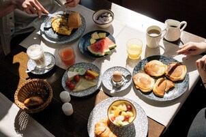 Ein Frühstückstisch mit Speisen, einer Kaffeetasse und einem Orangensaftglas.