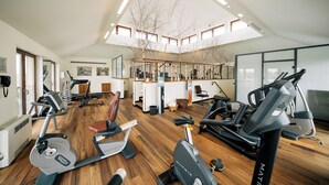 Un gimnasio con diverso equipo de ejercicio, una escalera y vista al cielo a través del techo.
