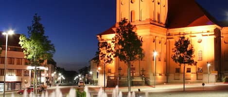 Ein historisches Gebäude mit einem markanten Turm und einem Brunnen davor.