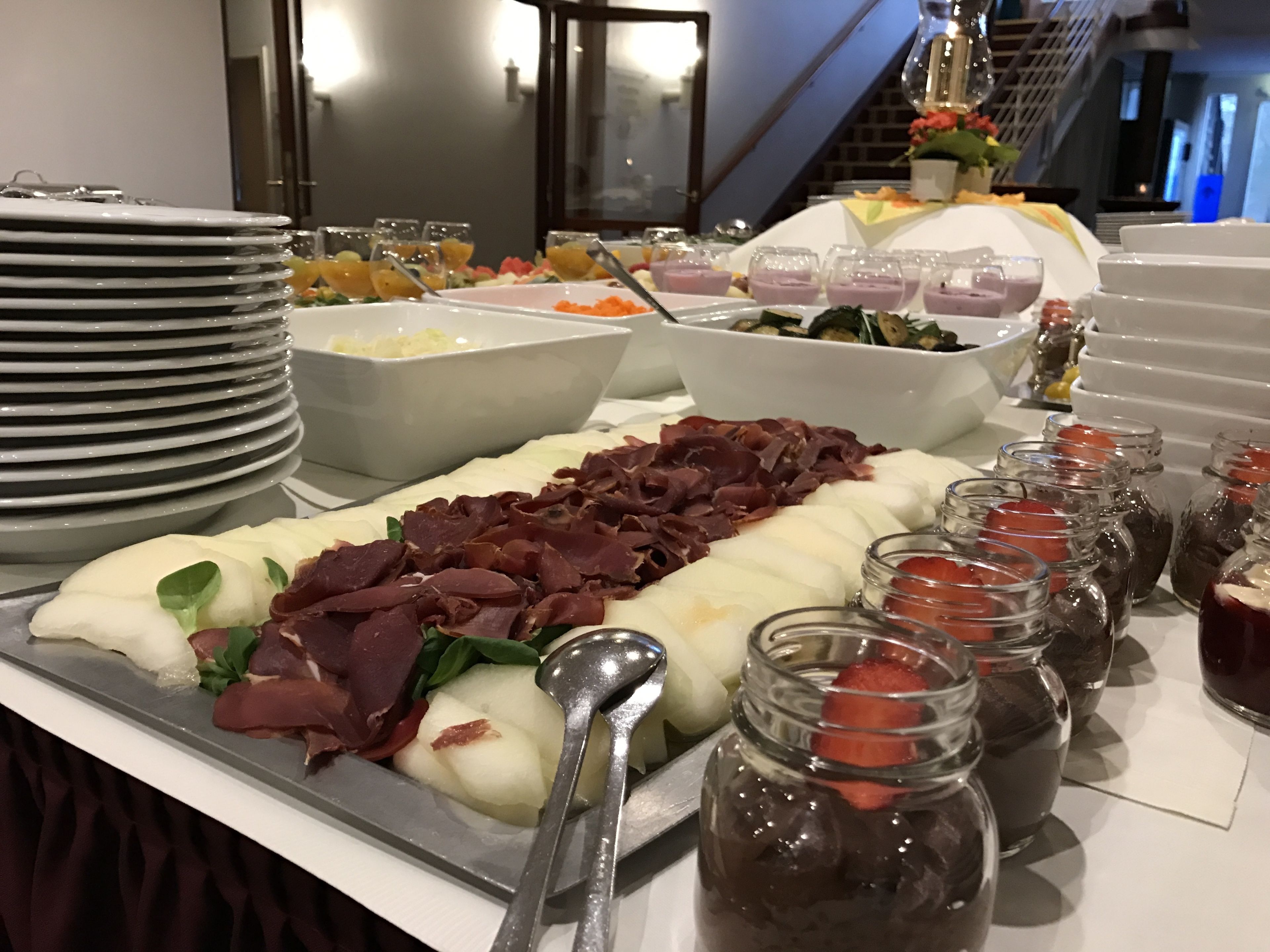 A buffet with various food items including meats, cheeses, and fruits.