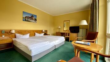 Ein Hotelzimmer mit einem großen Bett, einem Schreibtisch, einem Stuhl, einem Fernseher und einem Fenster mit Vorhängen.