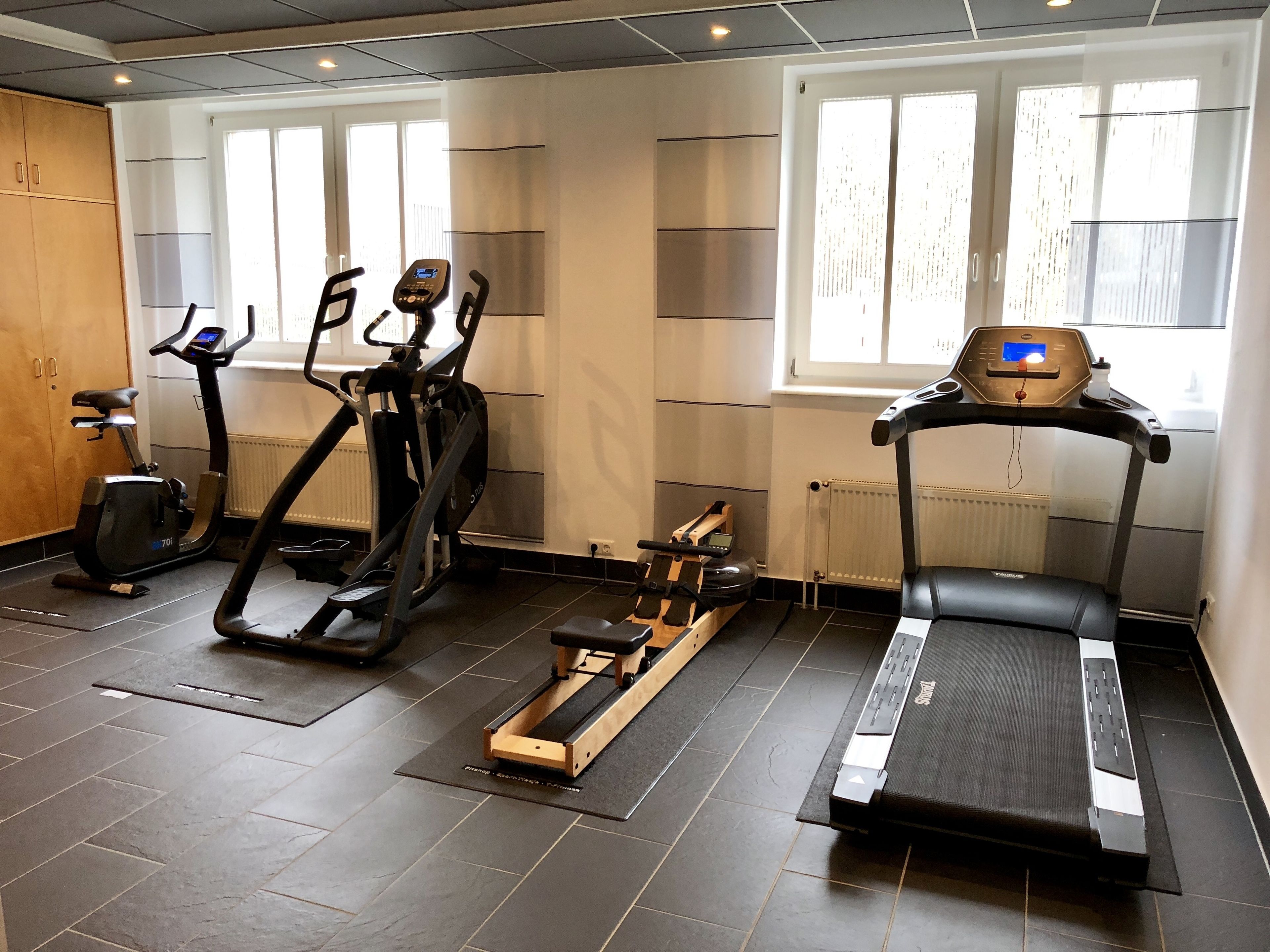 Un gimnasio con cintas de correr, elípticas y una máquina de remo.