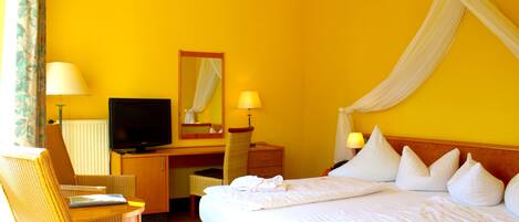 Una habitación de hotel con una cama, un escritorio, un televisor y una silla.