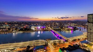 A nighttime cityscape with a river, illuminated bridges, and a Ferris wheel. - Oaks Brisbane Casino Tower Suites (Brisbane)