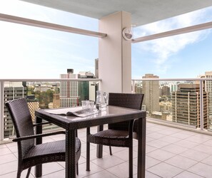 A balcony with a table and chairs, a pitcher, and glasses.