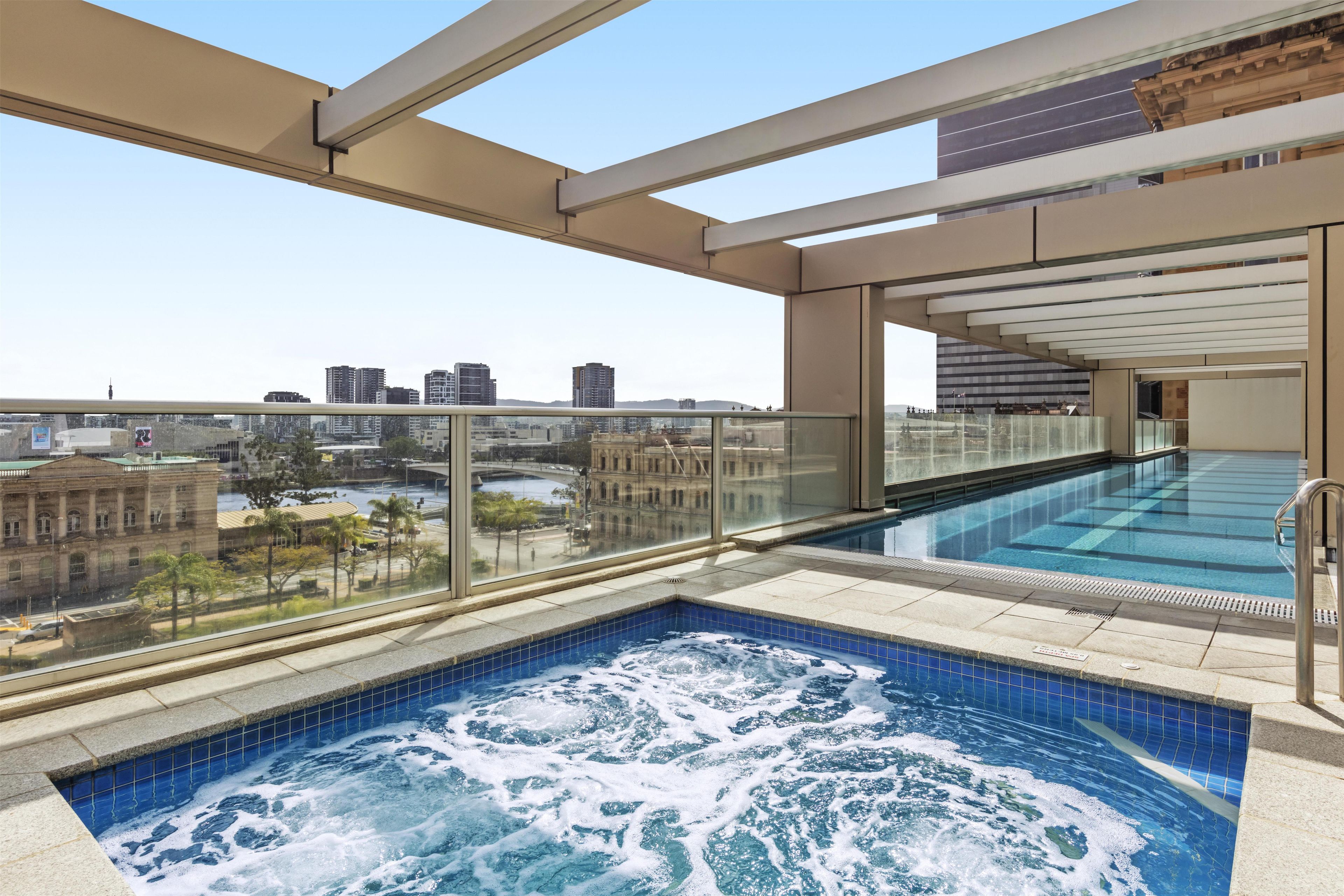 Piscina no terraço com vista para a paisagem urbana, incluindo um prédio grande e uma ponte.