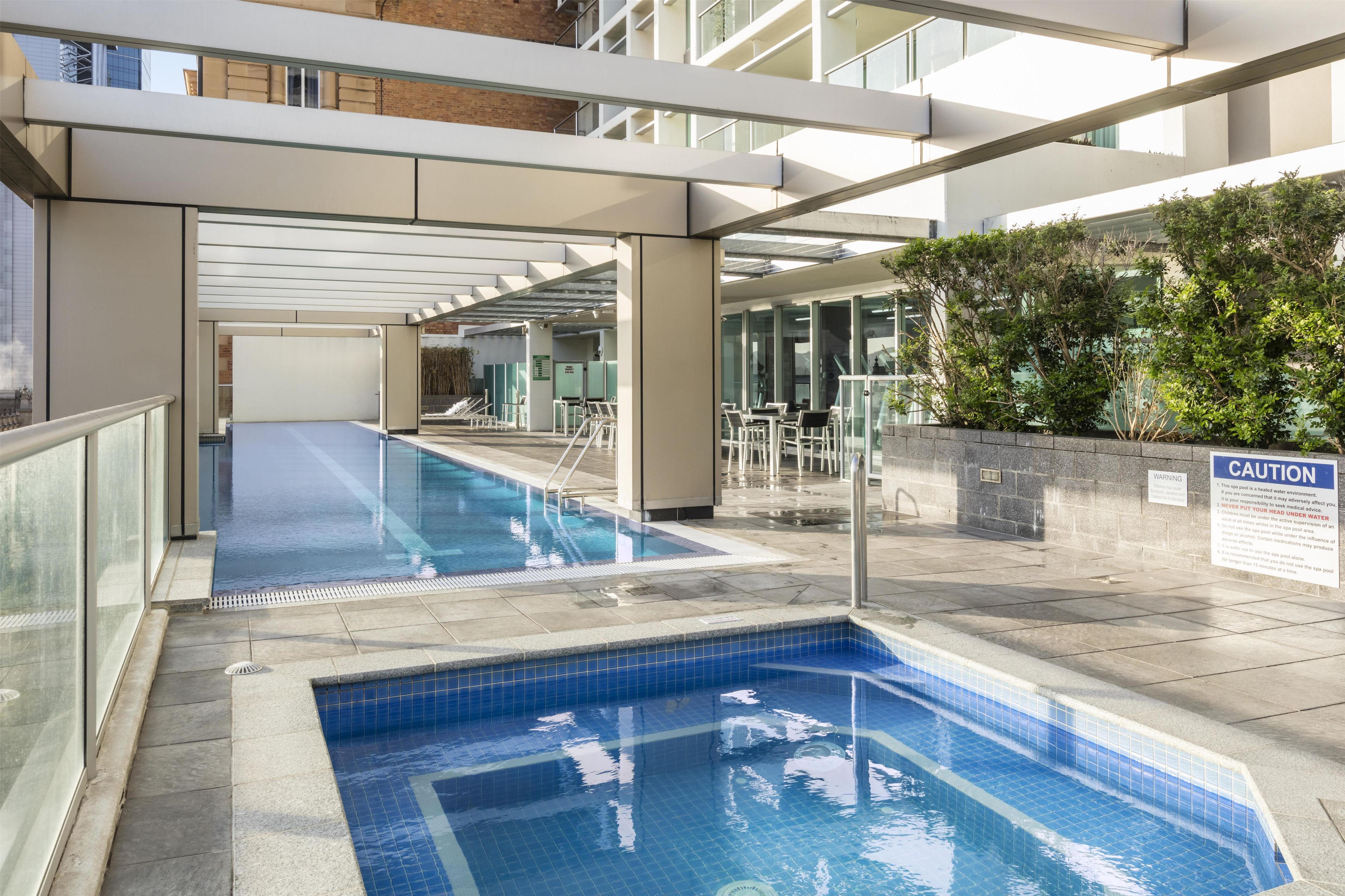 A swimming pool area with a caution sign, glass doors, and a seating area.