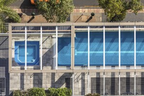 A building with a large swimming pool, a smaller hot tub, and a covered area with seating. - Oaks Brisbane Casino Tower Suites (Brisbane)