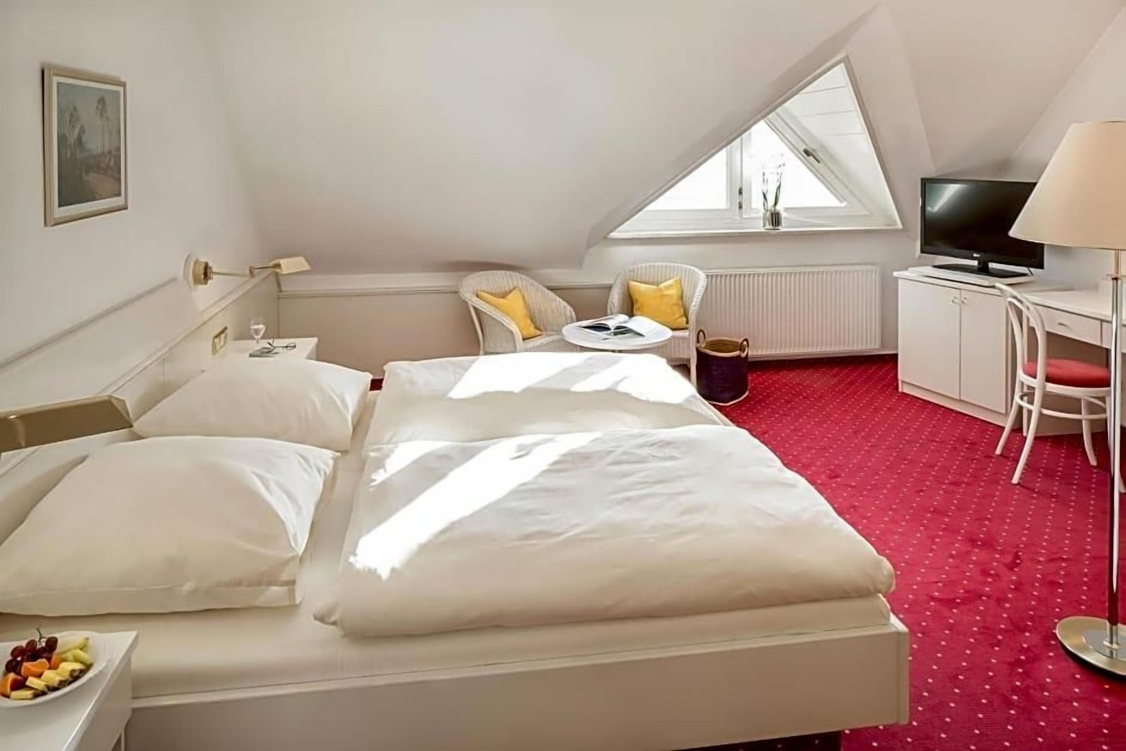 Ein Hotelzimmer mit einem Bett, einem Schreibtisch, einem Stuhl, einem Fernseher und einem Fenster.