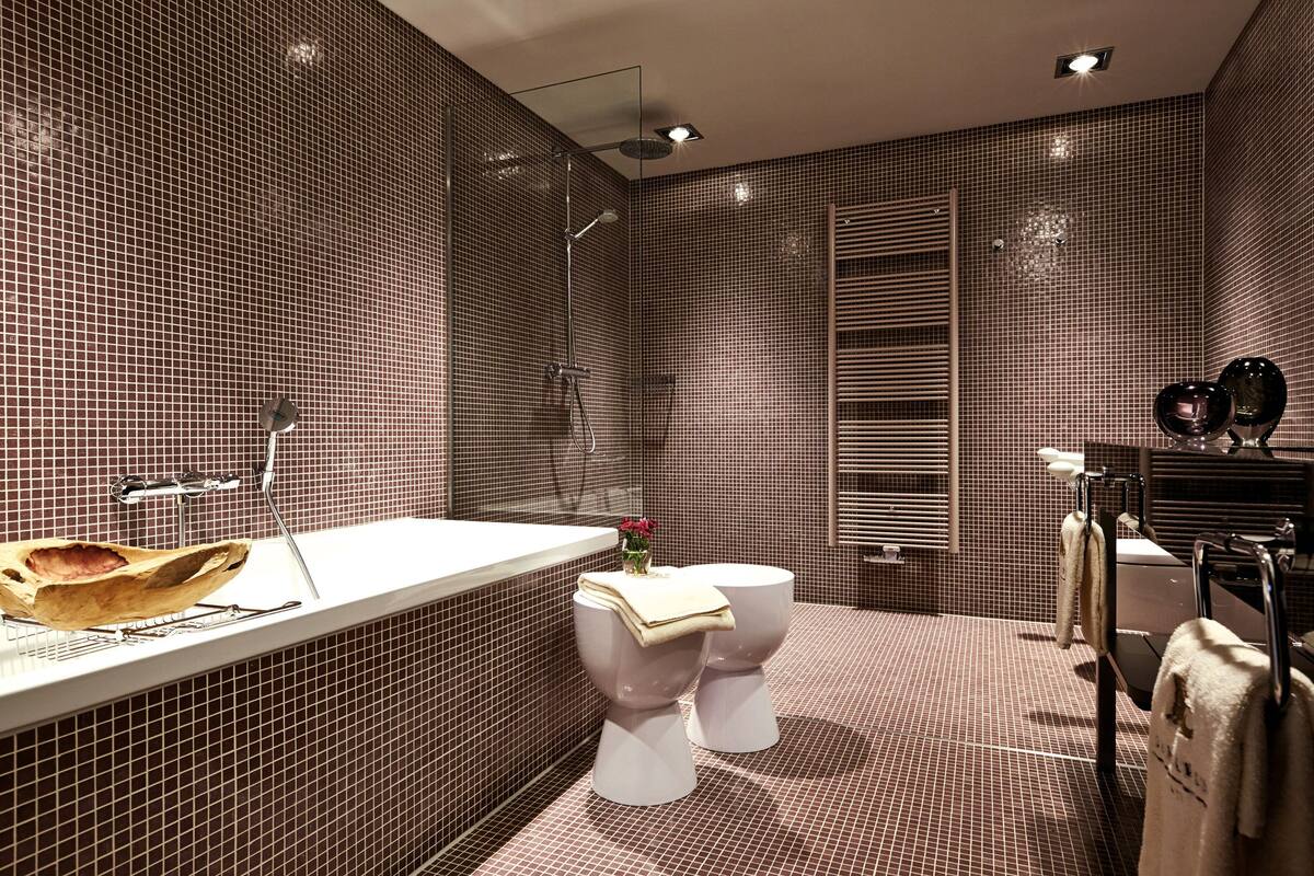 A modern bathroom with a large mirror, a white sink, and a toilet.