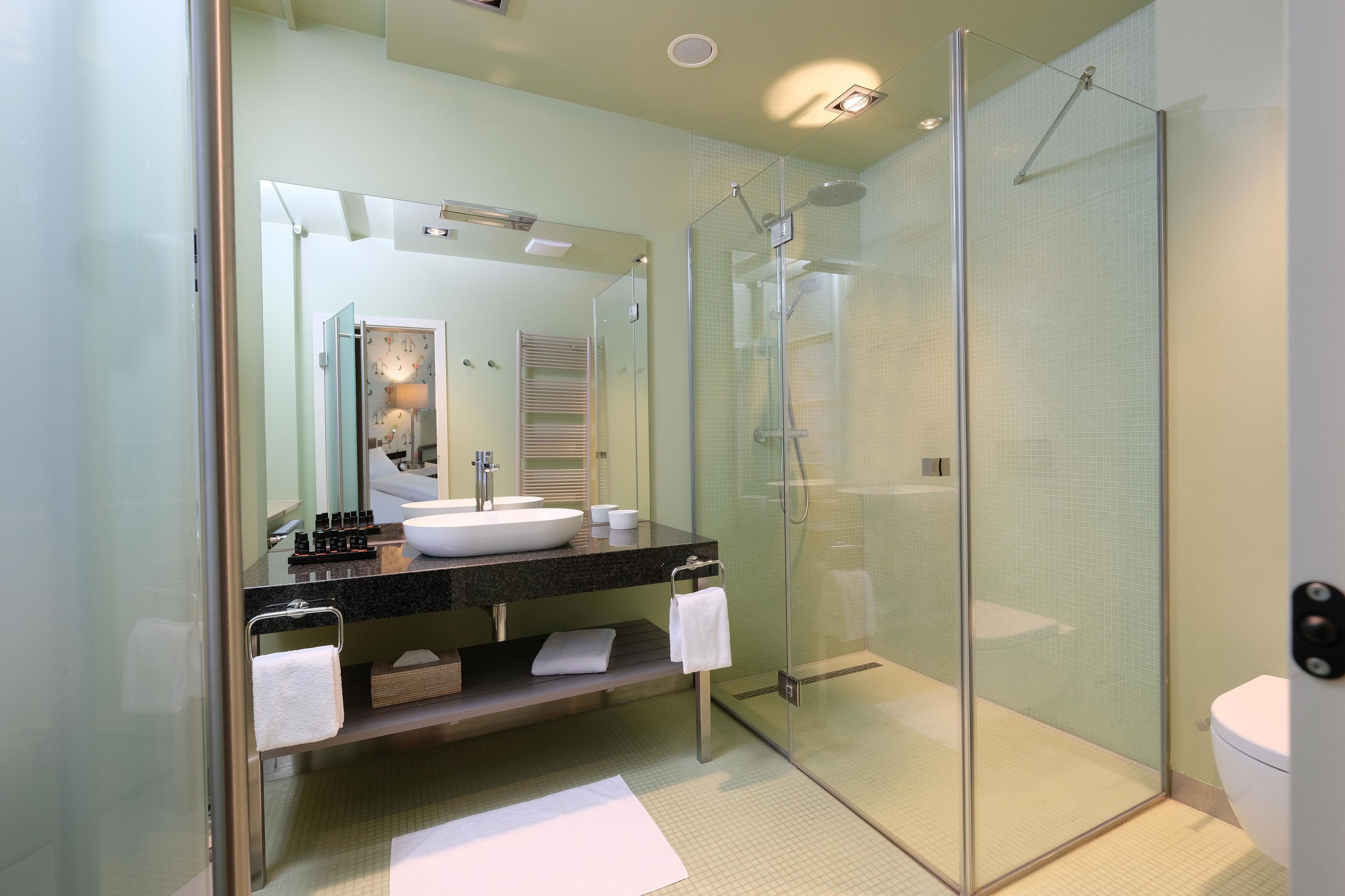 Ein modernes Badezimmer mit einer Duschkabine, einem großen Spiegel und einem weißen Waschbecken.
