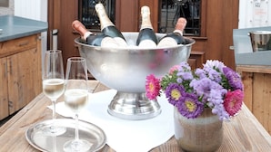Un restaurante de hotel llamado Zum Löwen con fachada de madera, un letrero sobre la entrada y una mesa con un cubo de champán, dos copas y un jarrón de flores.