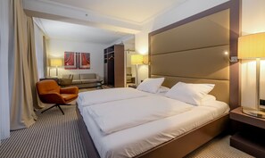 A hotel room with a large bed, a seating area with a sofa and chairs, and a wardrobe. - Zum Löwen Design Hotel Resort & Spa (Duderstadt)