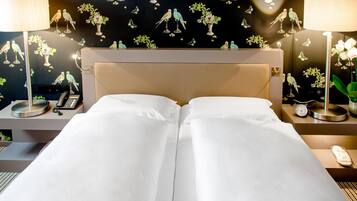 Una cama doble con sábanas blancas, un cabecero, mesitas de noche con lámparas, un teléfono y un reloj.