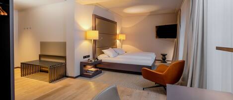 A hotel room with a bed, bedside lamps, a TV, a desk, and a chair.