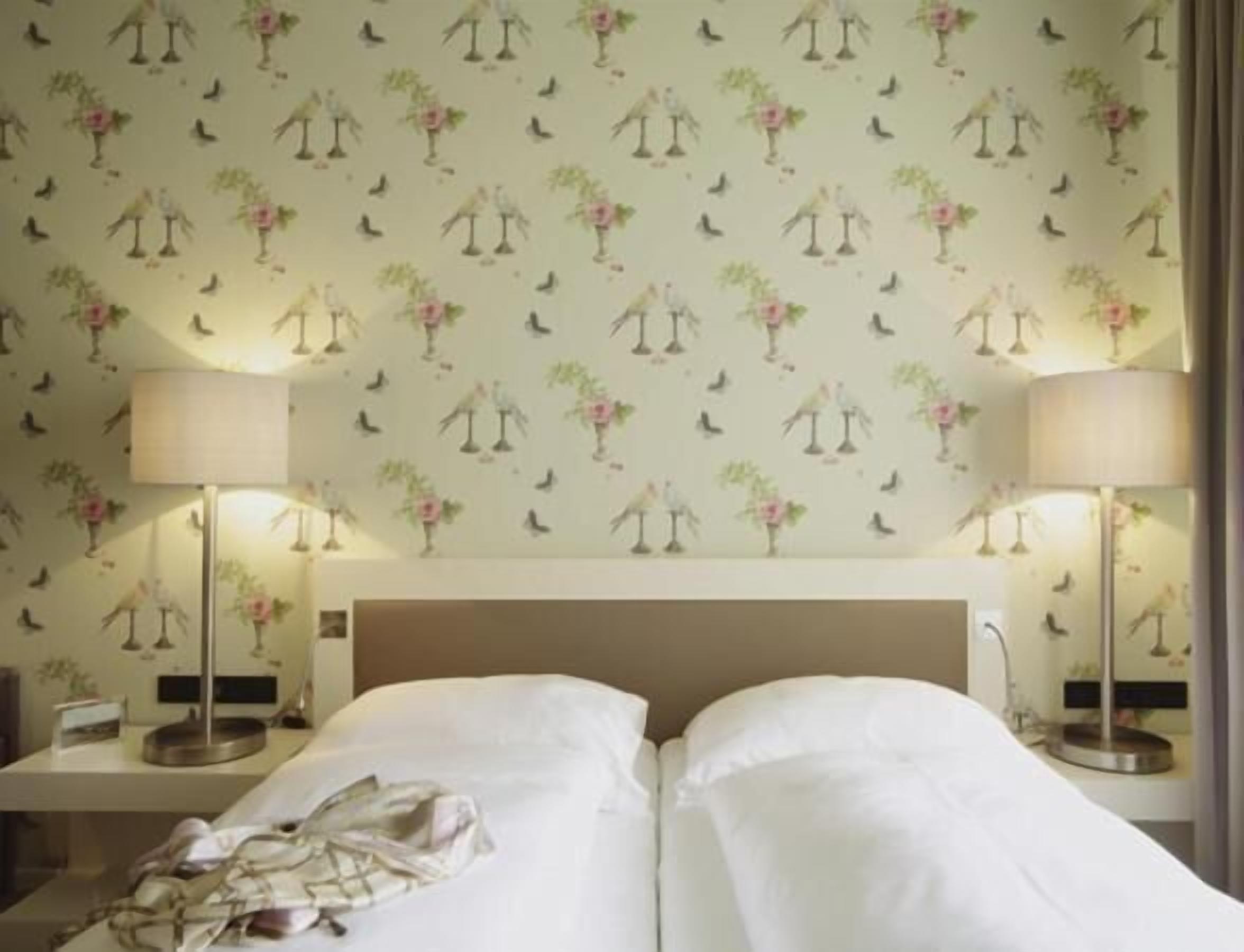 Een hotelkamer met twee bedden, een nachtkastje en twee lampen.