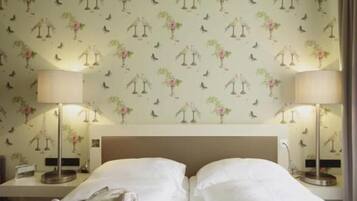 Een hotelkamer met twee bedden, een nachtkastje en twee lampen.