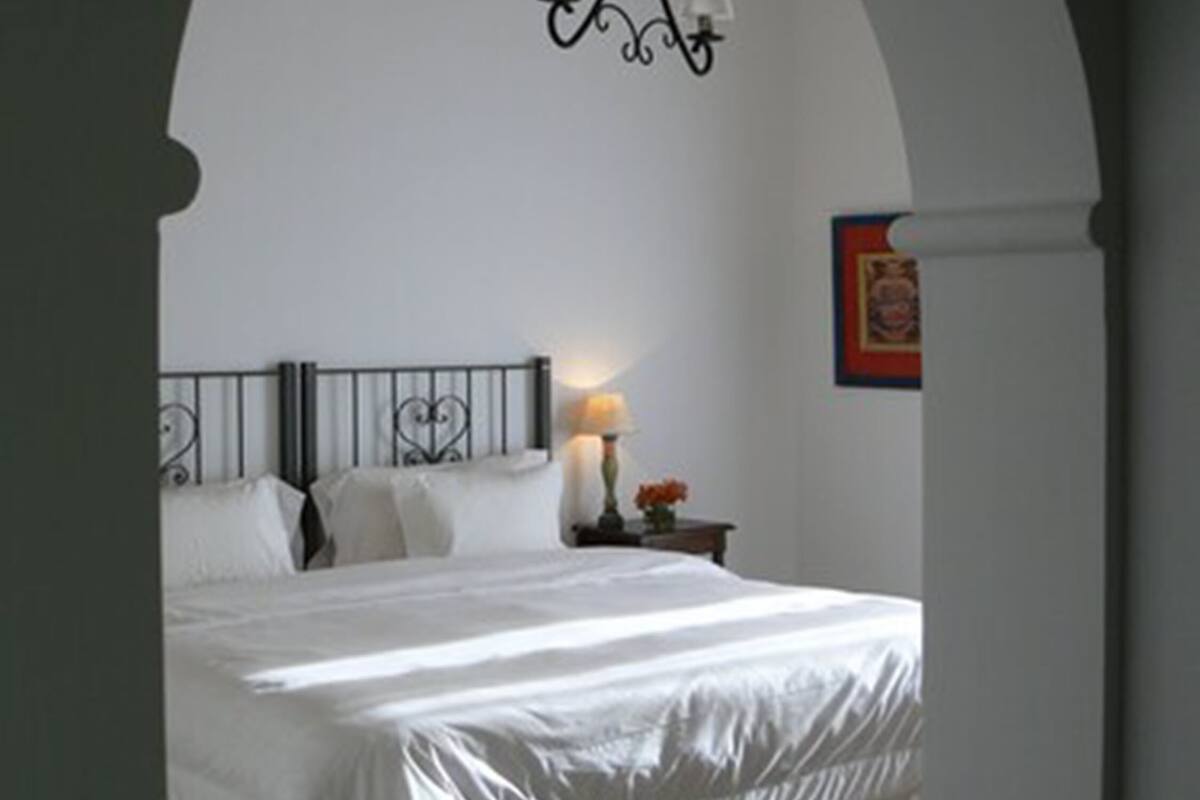 A bedroom with a bed, a nightstand, a lamp, and a chandelier.