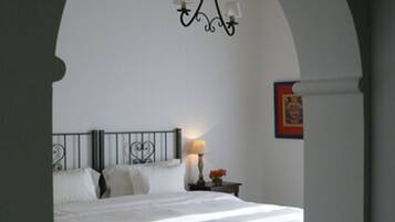 Un dormitorio con cama, mesita de noche, lámpara y candelabro.