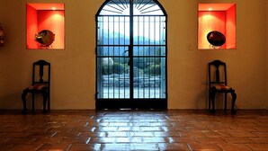 Ein Zimmer mit einer großen Bogenförmigen Tür, zwei Stühlen und Blick auf eine Berglandschaft durch die Tür.