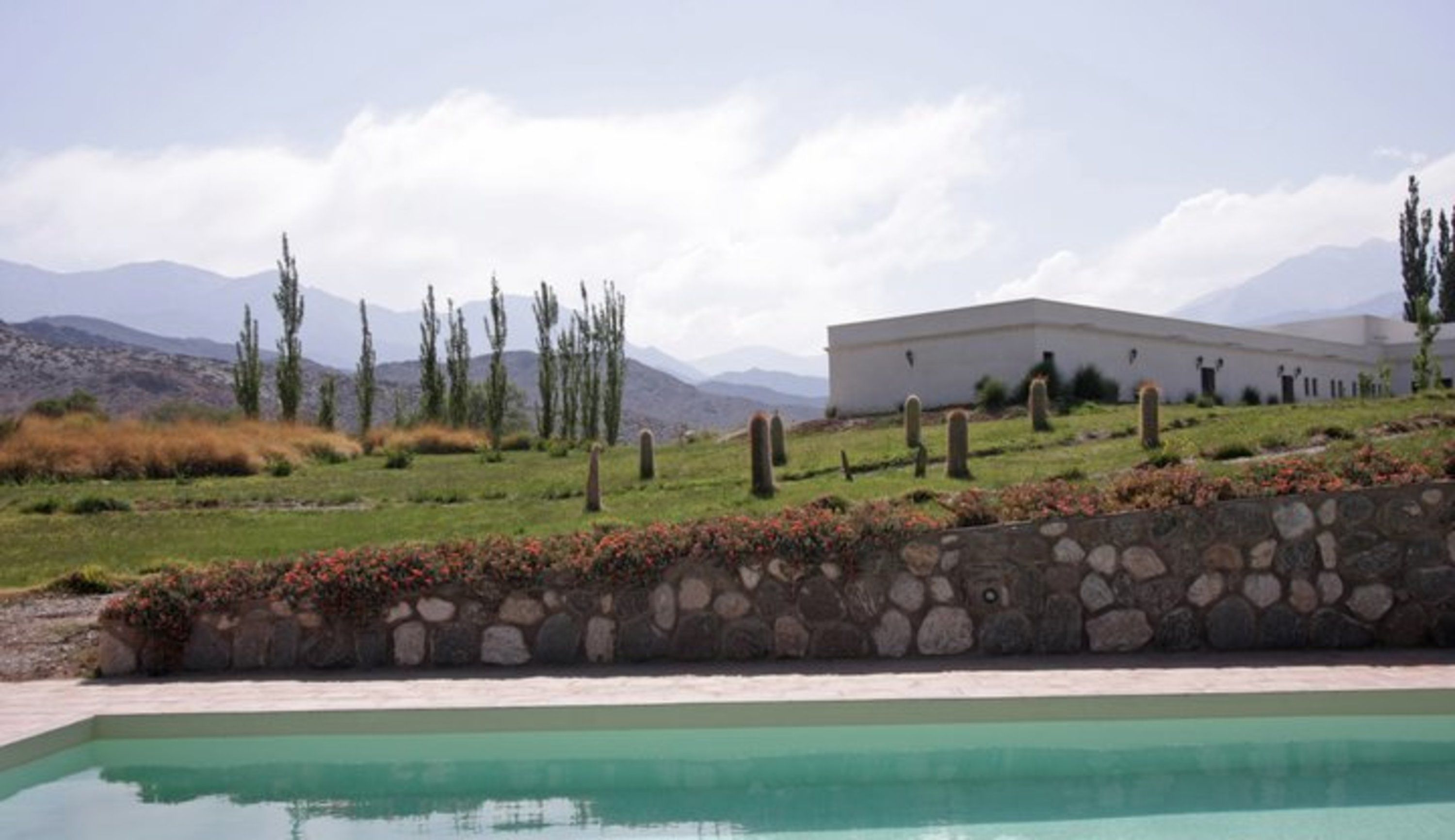 Una piscina con un muro de piedra y un edificio al fondo.