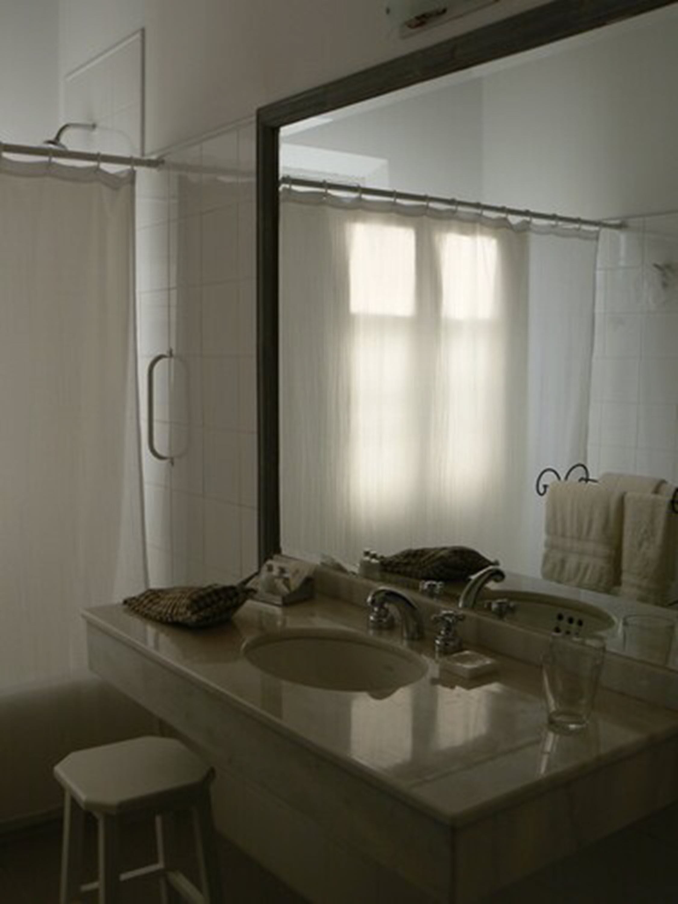 Une salle de bain avec un grand miroir, un lavabo, un porte-serviettes et un rideau de douche.